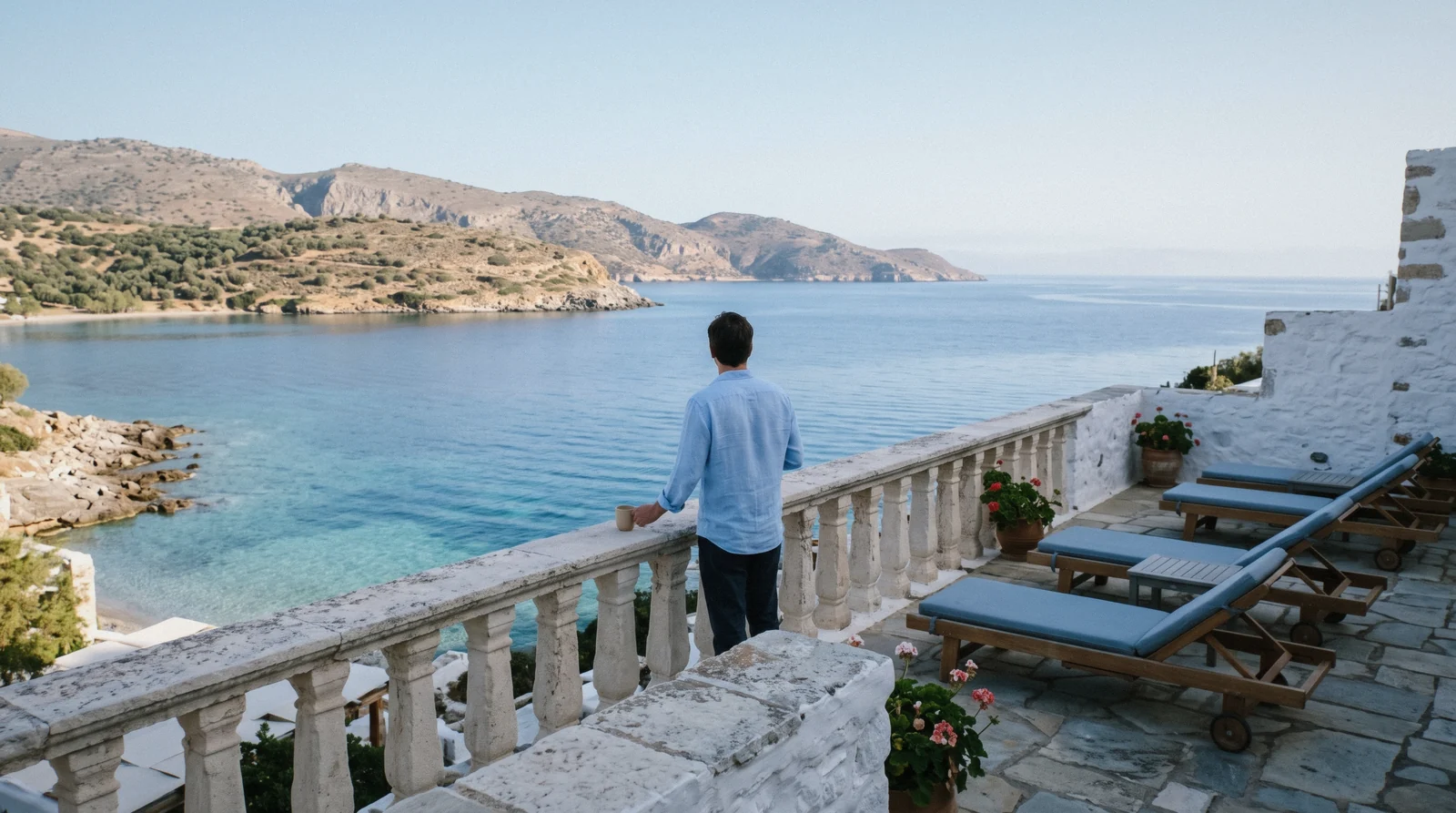 A quiet whitewashed hotel terrace overlooking a calm bay on the Crete coast in early morning light